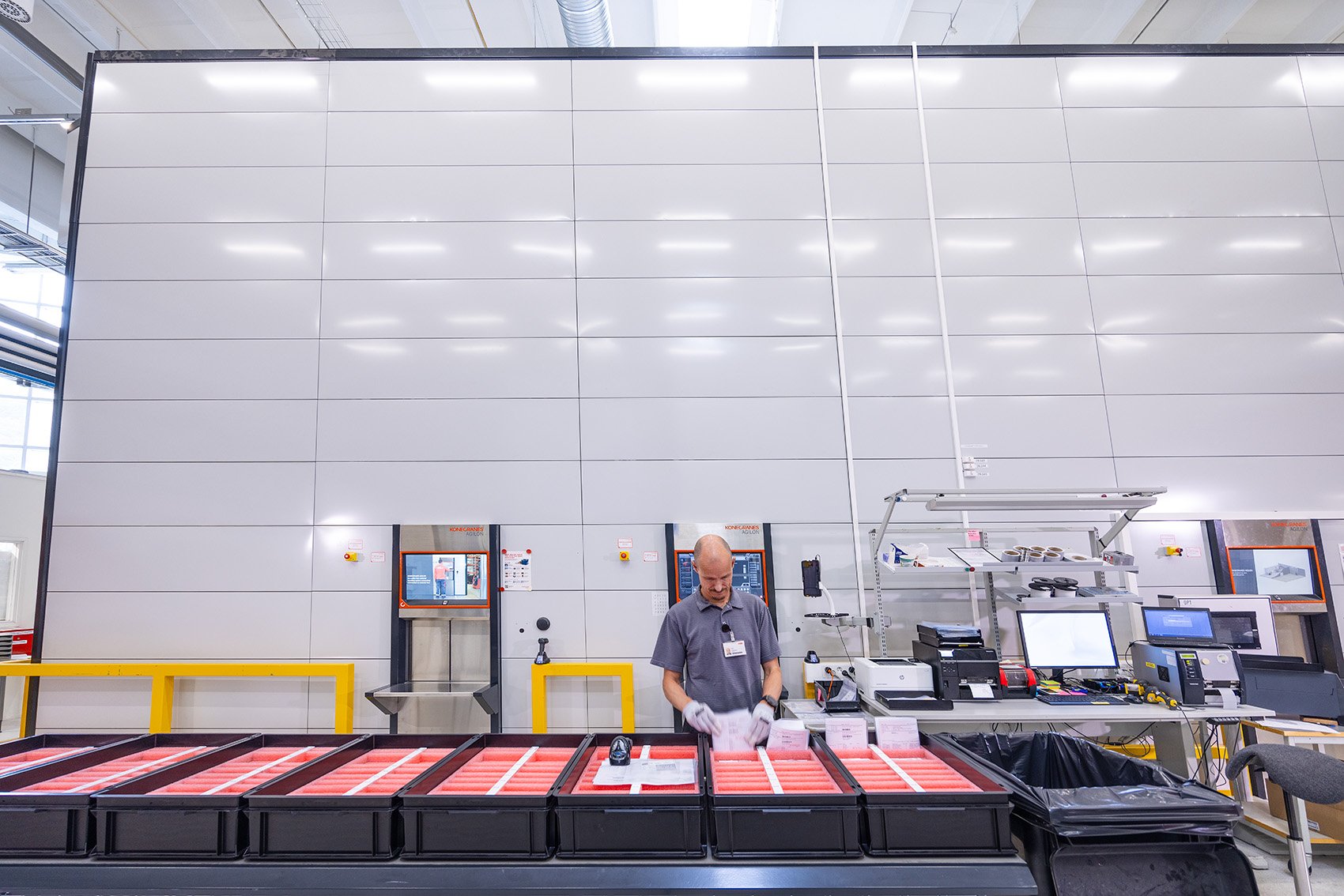 ABB Distribution Solutions' assembly picking workstation with a picker using Agilon warehouse automation and an ergonomic picking table. The setup ensures efficient and accurate picking, with the integrated Agilon warehouse system in the background.