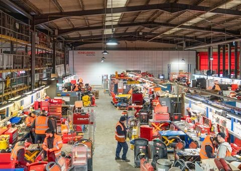 .A normal day at Speedy Services. People handling specialist equipment in work clothes. Agilon warehouse automation on the back space 